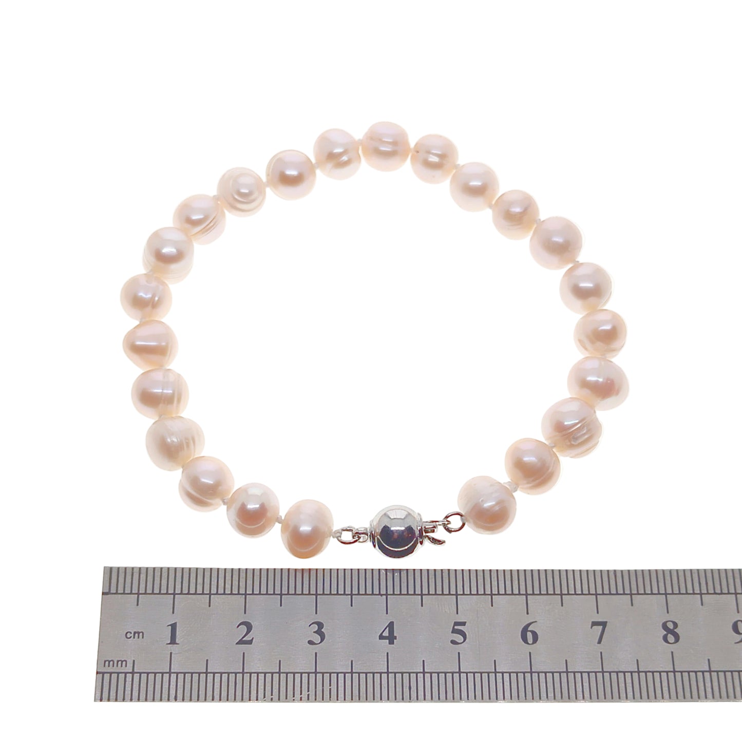 Pearl bracelet with a silver clasp on a white background, next to a ruler for size reference.
