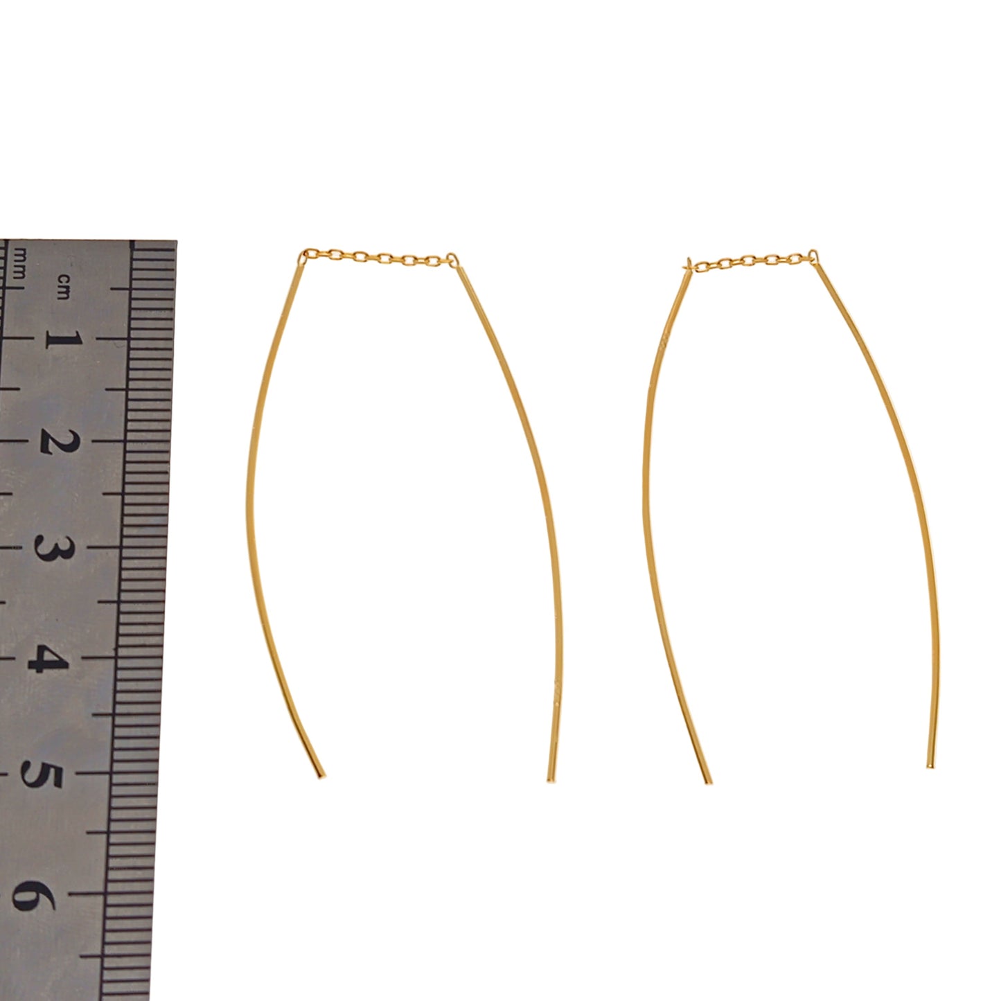Gold threader earrings with a ruler for scale on a white background