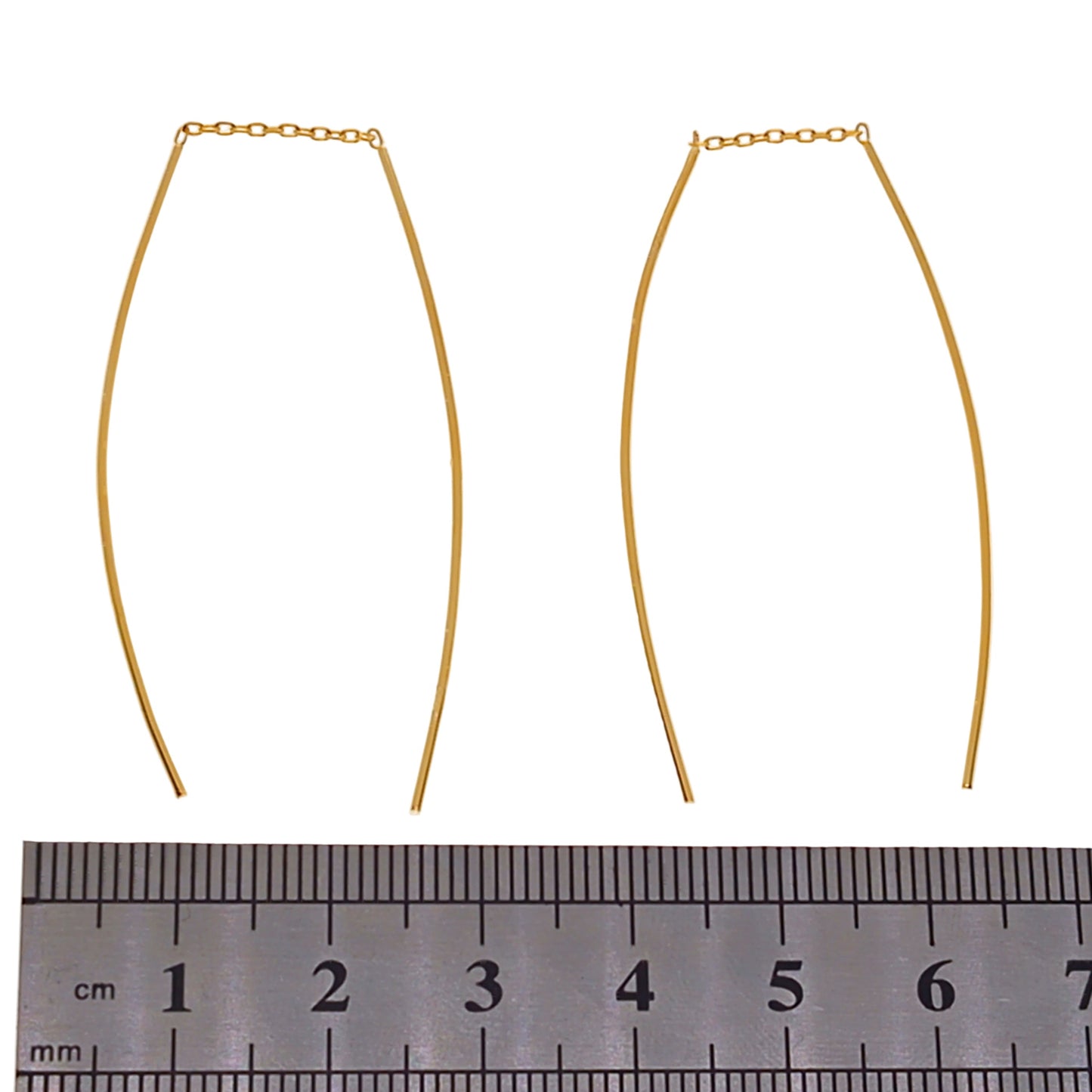 Gold threader earrings with a ruler for scale on a white background