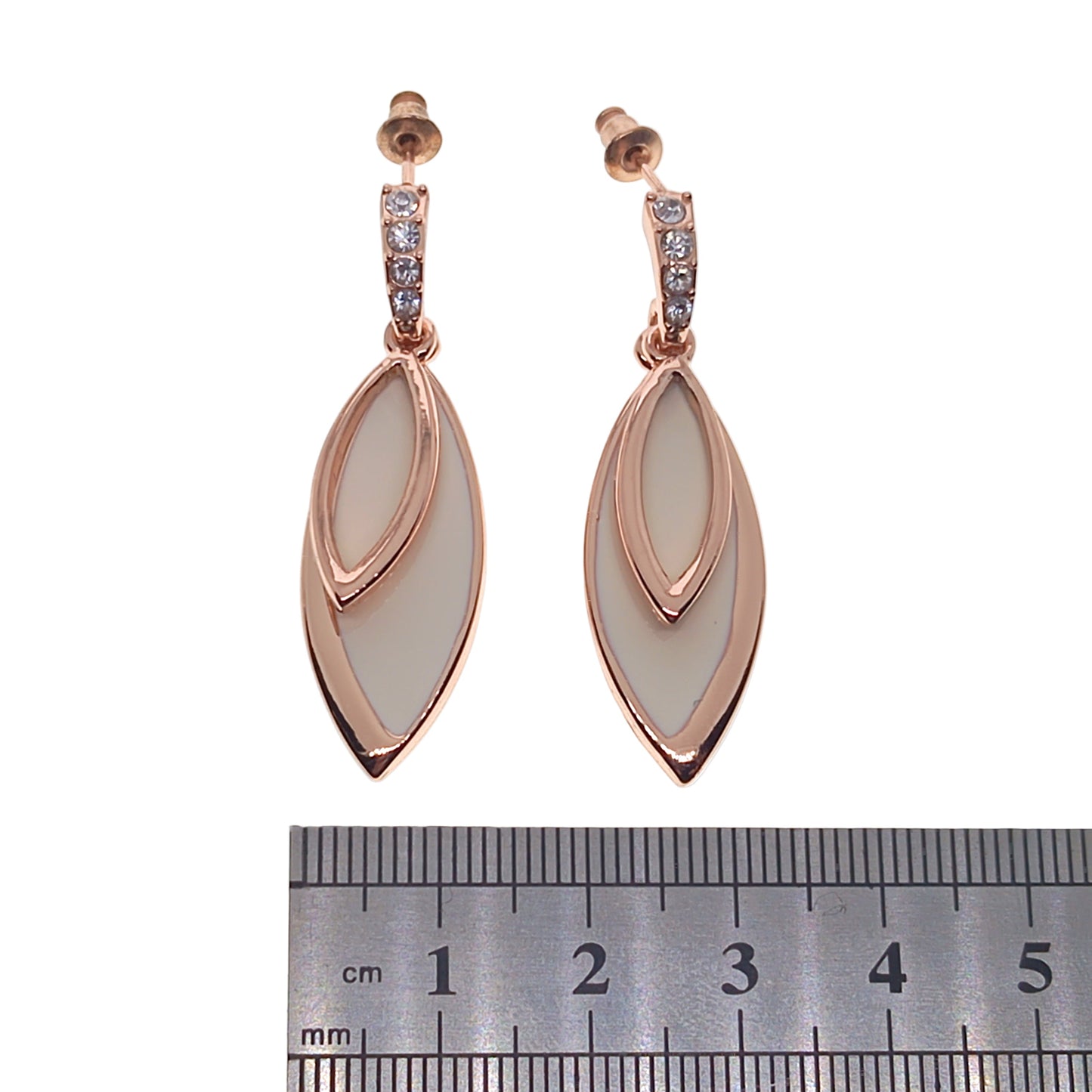 Rose gold earrings with white stones on a white background, accompanied by a ruler for scale.