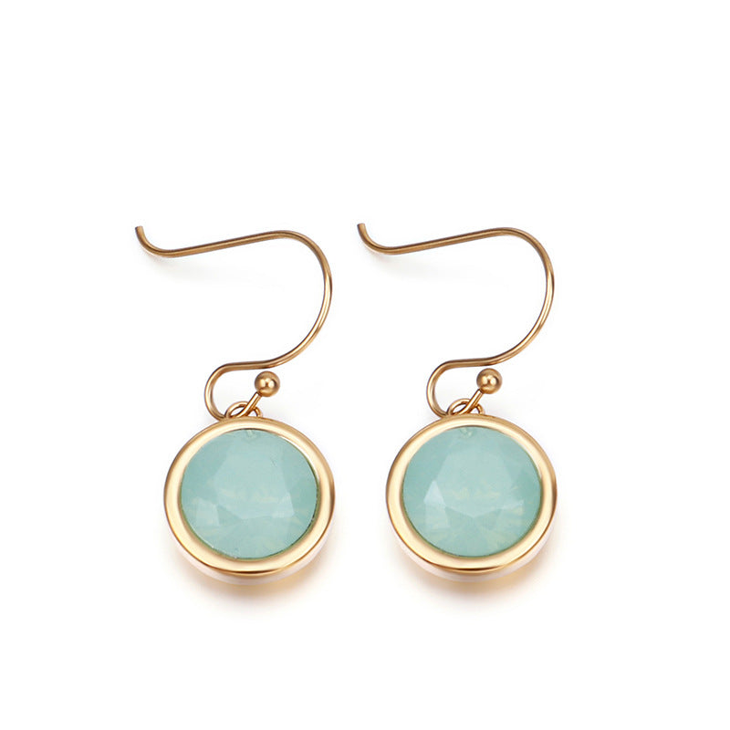 Gold earrings with green gemstones on a white background
