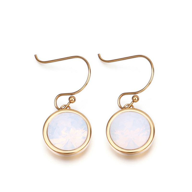Gold earrings with round, light-colored gemstones on a white background