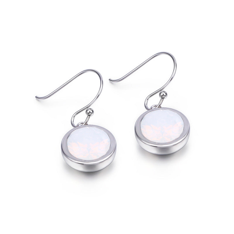 Silver earrings with round, light-colored gemstones on a white background