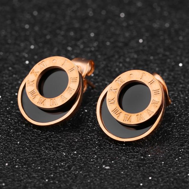 Rose gold earrings with circular design on a black textured background