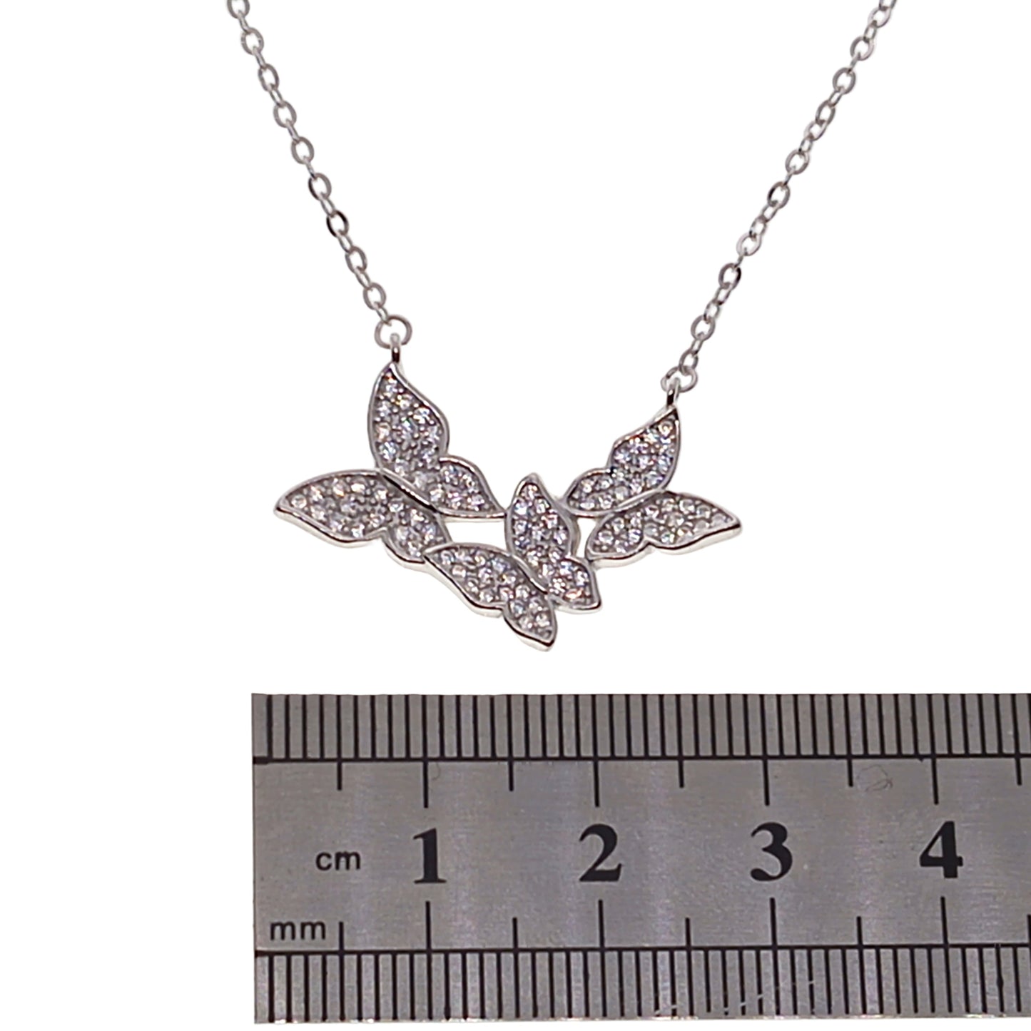 Silver necklace with leaf design next to a ruler for scale on a white background