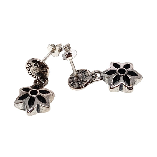 Silver earrings with black flower designs on a white background