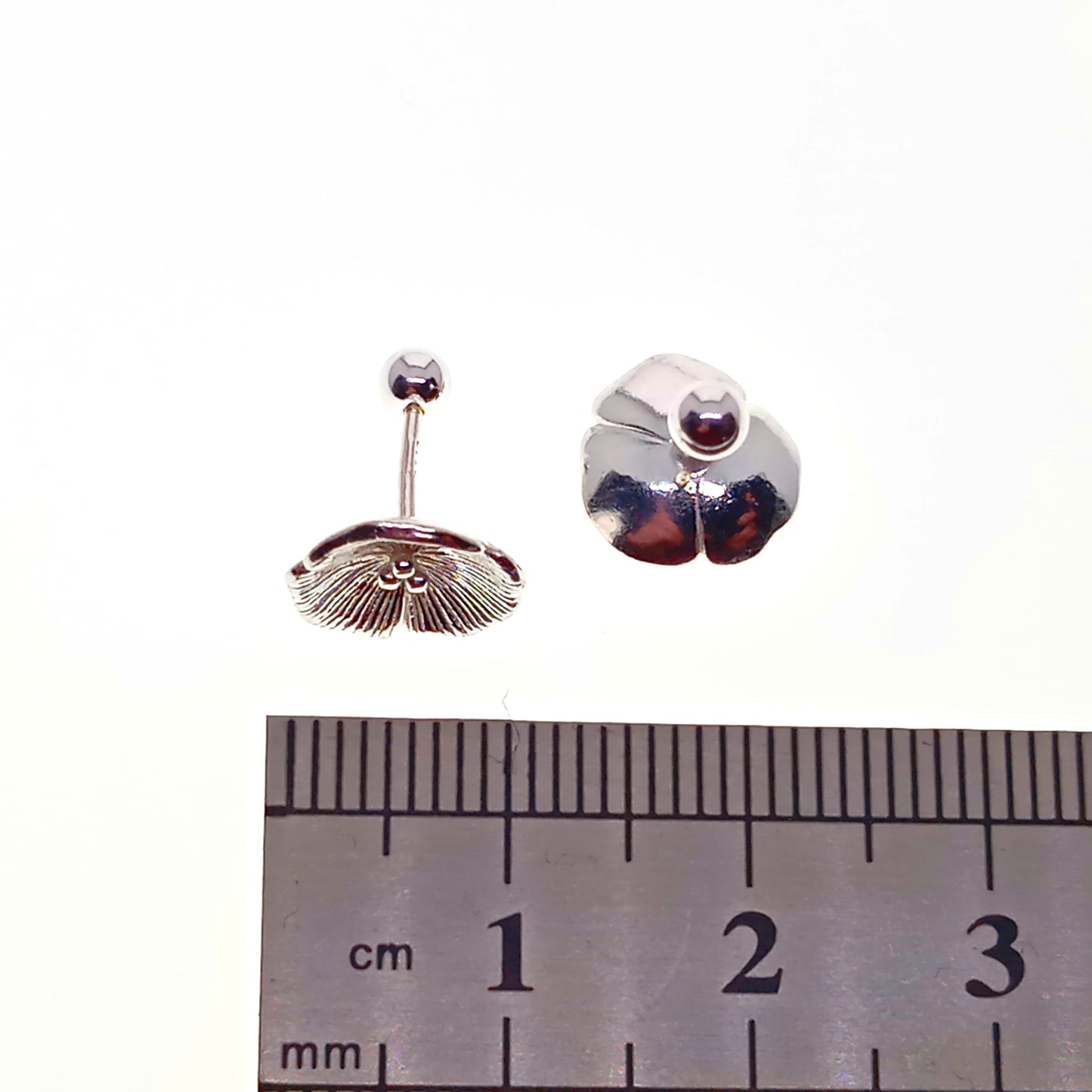 Pair of silver earrings with a central gemstone, shown next to a ruler for scale.