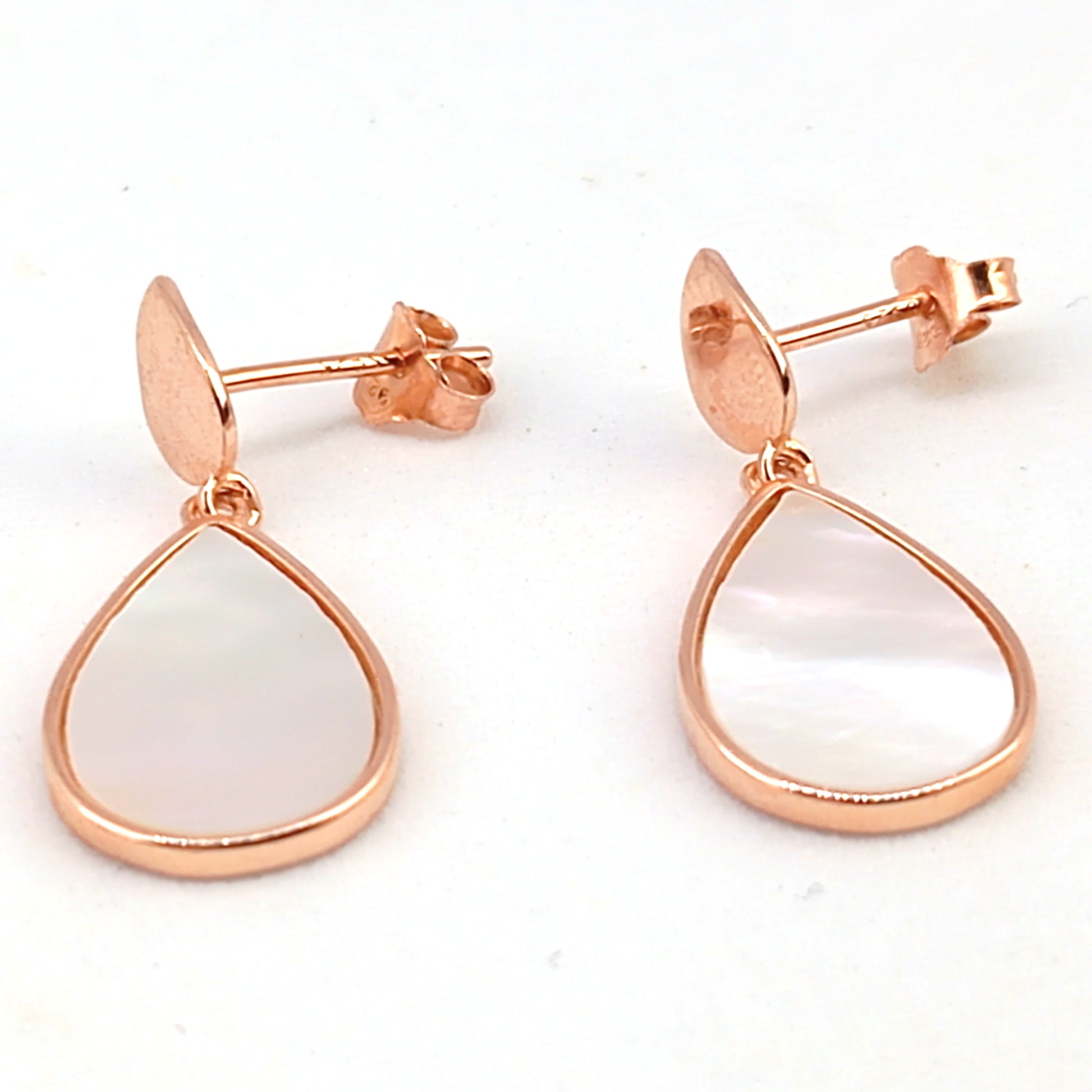 Rose gold earrings with teardrop-shaped white stones on a white background